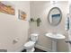 Charming half bathroom with pedestal sink, oval mirror, and decorative wall art and greenery at 105 Turnberry Trce, Sharpsburg, GA 30277
