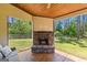 Cozy covered patio featuring a stone fireplace, wood ceiling, and view of the fenced backyard at 105 Turnberry Trce, Sharpsburg, GA 30277