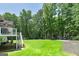 Expansive backyard featuring a large grassy area, mature trees, and a partially covered patio at 20 Allie Dr, Mcdonough, GA 30252