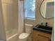 Bathroom including a vanity with dark countertop, round mirror, shower/tub, toilet, and window at 219 Maple Creek Chase, Woodstock, GA 30188