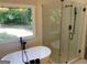 Bright bathroom features a freestanding tub, glass-enclosed shower with tiled walls, and a large window at 219 Maple Creek Chase, Woodstock, GA 30188