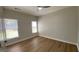 A simple, well-lit bedroom featuring a fan, wood-style floors, and two windows for natural light at 219 Maple Creek Chase, Woodstock, GA 30188