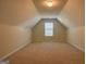 Finished attic with light carpet, lots of floor space, and a window bringing in natural light at 3008 Brighton Ct, Conyers, GA 30094