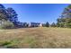 Expansive backyard view with a gentle slope, dotted with mature trees, and multiple houses in the distance at 3008 Brighton Ct, Conyers, GA 30094