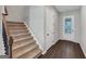 Foyer with wood-look flooring, staircase with carpeted steps and natural light from the glass paneled front door at 107 Cedar Brook Dr, Canton, GA 30115