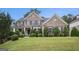 Imposing two-story brick home with manicured lawn and lush landscaping, shutters, and covered entry at 2750 Brentwood Estates Ct, Cumming, GA 30041