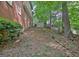 Backyard with a mix of leafy groundcover, bordered by an embankment, and a brick exterior in the background at 102 Passage Point, Peachtree City, GA 30269
