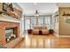 Bright living room with a brick fireplace, mantel, hardwood floors, and plantation shutters at 102 Passage Point, Peachtree City, GA 30269