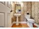 Charming powder room with pedestal sink, decorative mirror, and stylish wallpaper at 102 Passage Point, Peachtree City, GA 30269