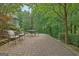 Stone patio with outdoor table and chair set surrounded by lush green foliage at 102 Passage Pt, Peachtree City, GA 30269