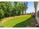 Large, green backyard with mature trees and a wooden fence, providing a private outdoor space at 30 Hollyhock Ln, Covington, GA 30014