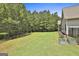 Spacious backyard with a black metal fence, mature trees, lush greenery, and charming garden beds at 45 Coral Ridge Ct, Palmetto, GA 30268