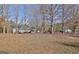 Leaf-covered backyard with small outbuilding and grass visible in the distance at 435 Crabapple Rd, Fayetteville, GA 30215