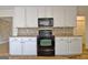 Charming kitchen with white cabinets, a black oven, and a unique stone backsplash at 435 Crabapple Rd, Fayetteville, GA 30215