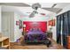 Charming bedroom with red accent wall, featuring a metal frame bed, hardwood floors, and a ceiling fan at 230 Vienna Way, Douglasville, GA 30134