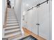 Hallway with wooden floors, white walls, sliding barn doors, and staircase at 3587 Candler Ct, Hapeville, GA 30354