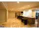 Basement wet bar with stone accents, travertine floors, and black barstools at 1010 Forest Overlook Sw Dr, Atlanta, GA 30331