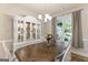 Bright dining room with a large window, a rustic wooden table, and elegant white chairs, ideal for Gathering meals at 344 Dylan Way, Mcdonough, GA 30252
