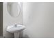 White pedestal sink with a round mirror on the wall in this minimalist bathroom at 2714 Haynescrest Dr, Grayson, GA 30017