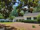 View of the charming one-story home framed with mature tree branches and lush green foliage at 7640 Ryefield Dr, Sandy Springs, GA 30350