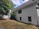 Side view of a white brick home featuring windows with white trim, set against a backdrop of mature trees and greenery at 7640 Ryefield Dr, Sandy Springs, GA 30350