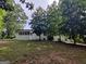 Back exterior view of home surrounded by mature trees and a lush, green lawn at 7640 Ryefield Dr, Sandy Springs, GA 30350