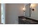 Bathroom vanity with dark wood cabinetry, black granite countertop and sconces at 10765 Shallowford Rd, Roswell, GA 30075