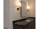 Bathroom vanity with dark wood cabinetry, black granite countertop and sconces at 10765 Shallowford Rd, Roswell, GA 30075