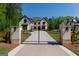 Elegant home with decorative iron gate and brick pillars on a manicured lawn, providing curb appeal and security at 10765 Shallowford Rd, Roswell, GA 30075