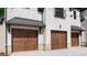 Exterior view of a three car garage with natural stained wood doors and metal overhangs at 10765 Shallowford Rd, Roswell, GA 30075