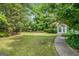 Manicured backyard with lush green grass, a white house, and a gazebo set back in the wooded area at 19 Indian Bluff Dr, Sharpsburg, GA 30277