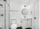Modern bathroom with a glass shower, tile floors, a round mirror, and a toilet at 5490 Chemin De Vie, Sandy Springs, GA 30342