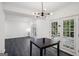 Minimalist dining room with modern lighting fixture and an eye to the sunlit garden through glass doors at 5490 Chemin De Vie, Sandy Springs, GA 30342
