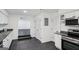 Modern kitchen with white cabinets, stainless steel appliances, and dark countertops and floors with arched entryway at 5490 Chemin De Vie, Sandy Springs, GA 30342