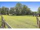 Large green pasture surrounded by trees, with a white fence and horse barn at 109 Cannon Road, Sharpsburg, GA 30277