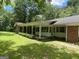 A glimpse of a cozy brick home showing the covered porch and an open lawn with lots of shade trees at 2934 Union Grove Rd, Conyers, GA 30012