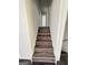 A staircase features dark wood-look steps with white risers and stringers leading to a hallway with a white door at 7340 Chalk Way, Riverdale, GA 30296