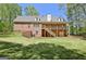 A full backyard view of a brick home with a covered deck and lush green space for outdoor activities at 315 Antebellum Way, Fayetteville, GA 30215