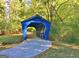 A charming blue covered bridge surrounded by lush greenery, creating a picturesque scene at 315 Antebellum Way, Fayetteville, GA 30215