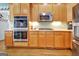 A closer view of the wood cabinets, stainless double oven, microwave, and cooktop in kitchen at 315 Antebellum Way, Fayetteville, GA 30215