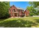 Charming two-story red brick home with a well-manicured lawn, lush landscaping, and mature trees at 255 Hidden Lake Dr, Fayetteville, GA 30215