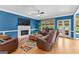 Cozy living room boasts blue walls, hardwood floors, fireplace, and leather furniture with a ceiling fan at 255 Hidden Lake Dr, Fayetteville, GA 30215