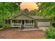Single-story home featuring a quaint front porch and a two-car attached garage in a wooded setting, with sunset view at 1638 River Trc, Auburn, GA 30011
