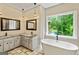 Luxurious bathroom featuring a soaking tub, double vanities, and a large window with a private backyard view at 324 Chimney Sweep Cir, Peachtree City, GA 30269