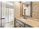 Bathroom featuring granite countertop, gray cabinets, and mosaic backsplash, with the view into the toilet/shower room at 324 Chimney Sweep Cir, Peachtree City, GA 30269