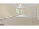 Bedroom featuring neutral carpet, walls, and trim, ceiling fan, and window with wooded backyard view at 324 Chimney Sweep Cir, Peachtree City, GA 30269