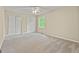 Bedroom with neutral carpet, paint, and trim, double closets, ceiling fan, and views of wooded yard at 324 Chimney Sweep Cir, Peachtree City, GA 30269