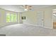 Bedroom with neutral carpet and walls, ceiling fan, and door to bathroom, bright window, and mounted TV at 324 Chimney Sweep Cir, Peachtree City, GA 30269