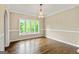 Dining room featuring hardwood floors, a chandelier, a large window with backyard views, and white trim at 324 Chimney Sweep Cir, Peachtree City, GA 30269