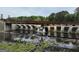 Scenic view of Lake Peachtree featuring a dam, bridge and flowing water amidst lush greenery on a sunny day at 120 Bowfin Bay, Peachtree City, GA 30269